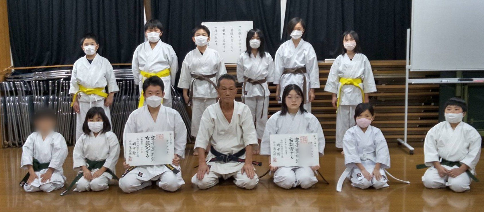 段位の認定証を手にした道場生と、先生を囲んだ集合写真