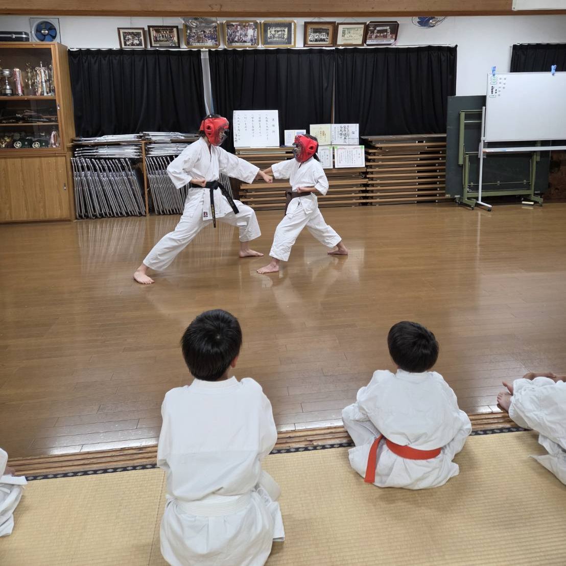 防具をつけて組手の稽古をする子どもたちと、座って見守る道場生